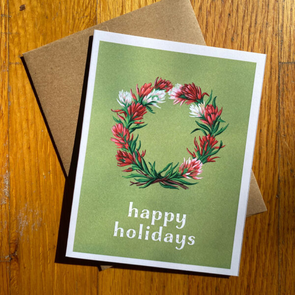 Paintbrush Wreath Holiday Card featuring Red and white Indian Paintbrush flowers in a wreath shape on a green background. Below it reads "happy holidays"