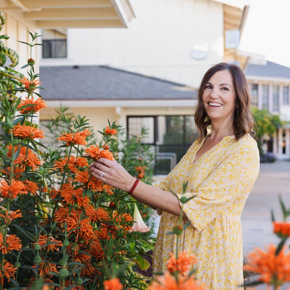 Erin Hunter, artist, looks at flowers in front of her house