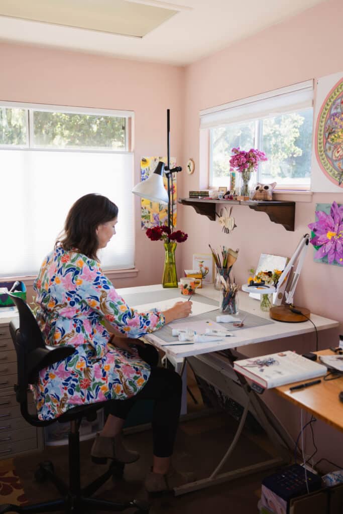 Erin painting a botanical illustration in her home art studio